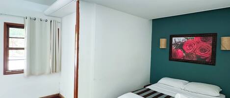 Een hotelkamer met een bed, een raam met gordijnen, een schilderij aan de muur en een betegelde vloer.