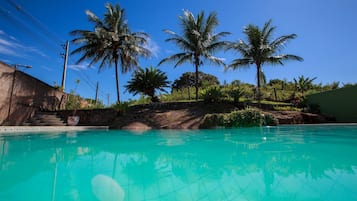 Una piscina al aire libre, sillones reclinables de piscina