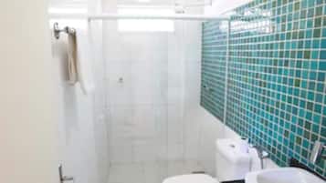 Casa de banho com cabine de duche em vidro, sanita e lavatório com bancada preta.