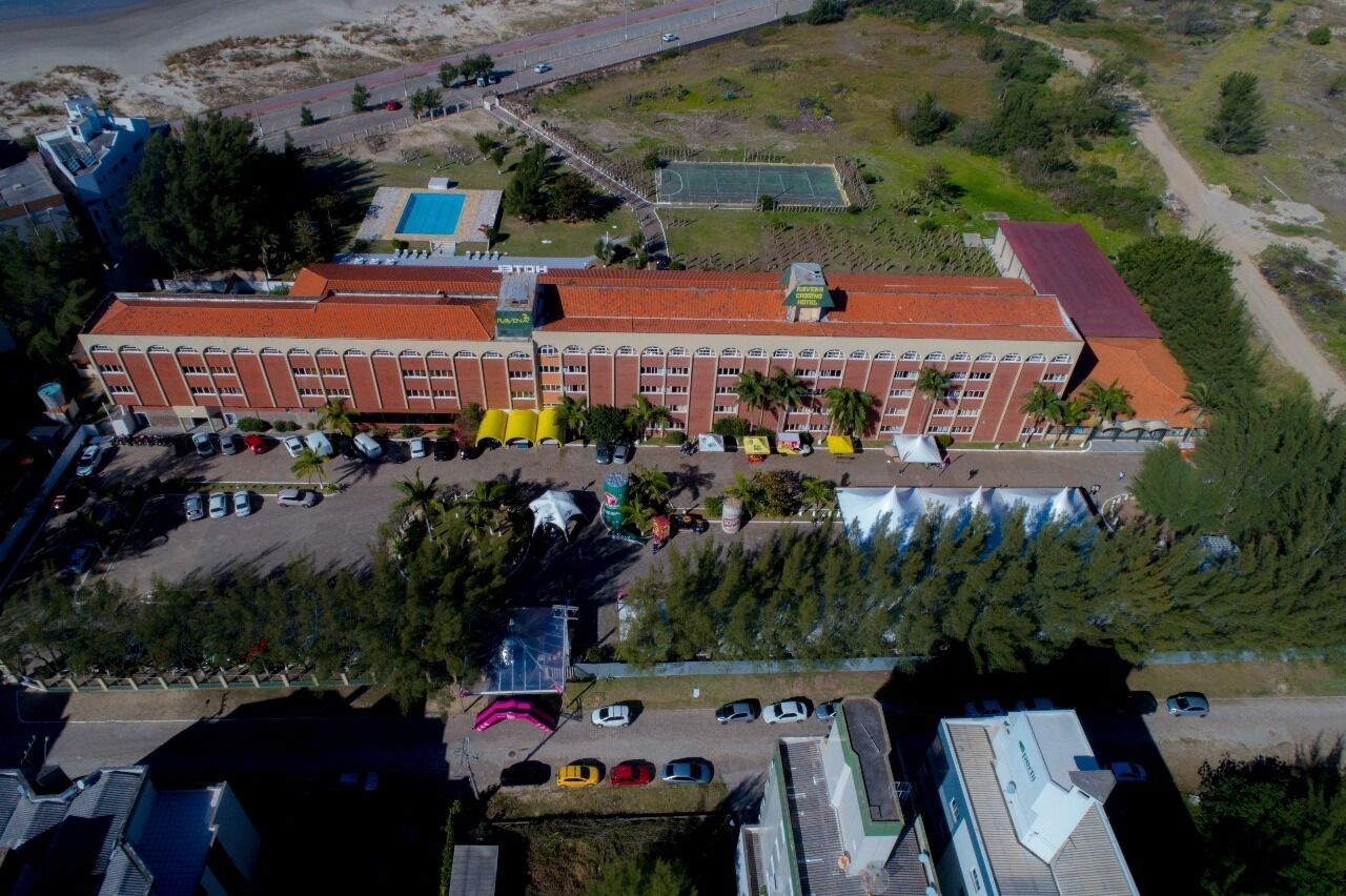 Vista aérea de un hotel con varias edificaciones, un estacionamiento y un campo deportivo.