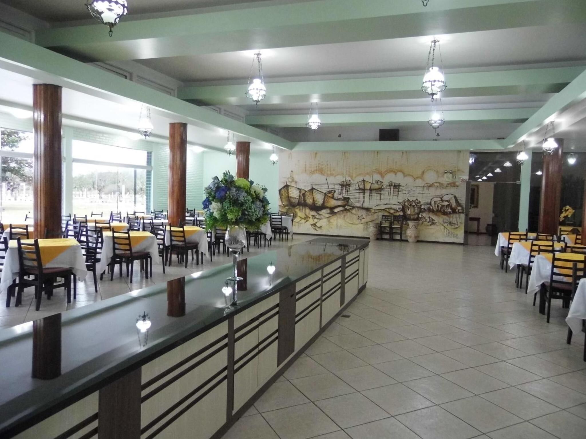 Un amplio comedor con mesas y sillas, una barra central y un mural en la pared de fondo.