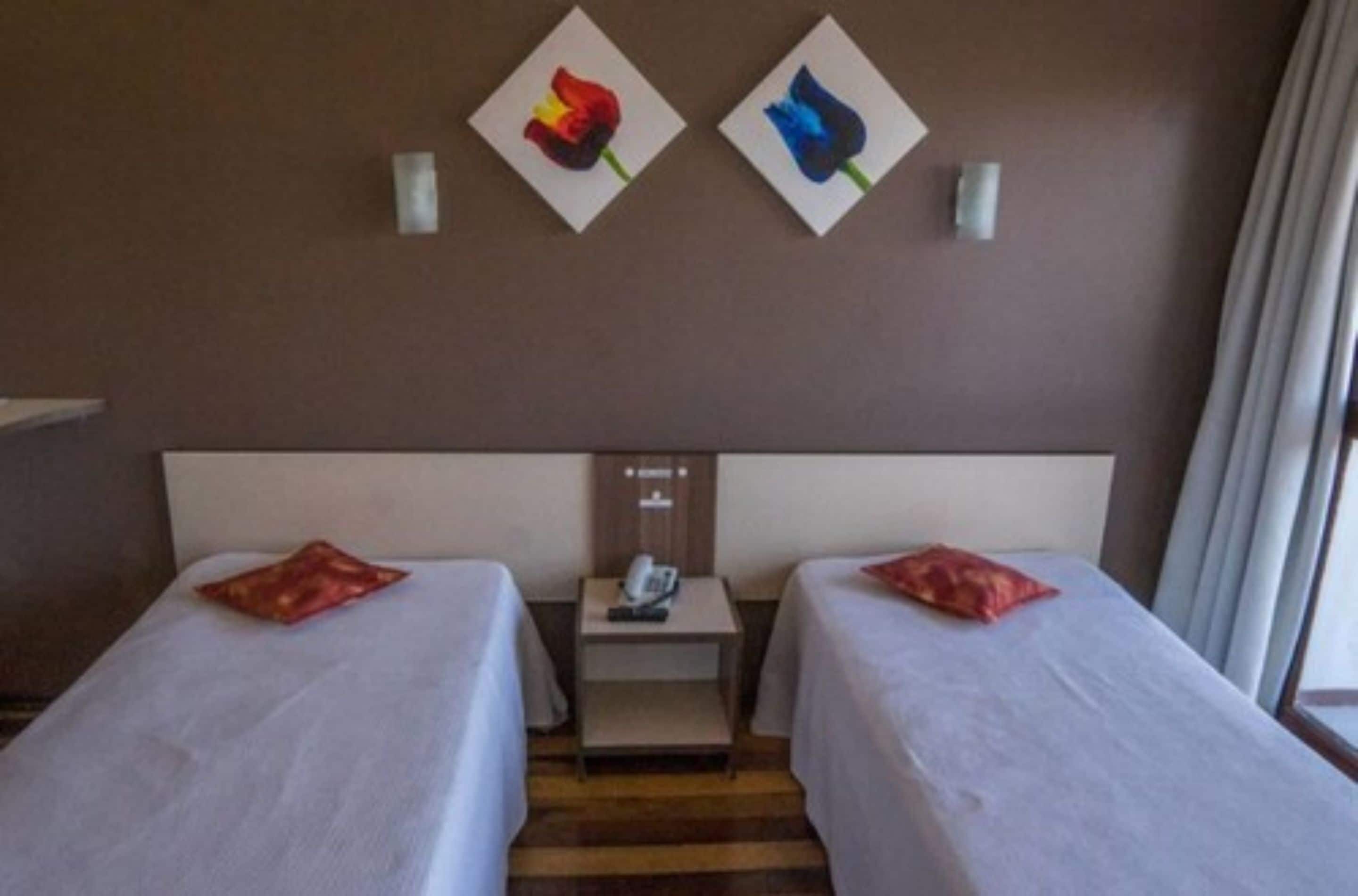 Habitación de hotel con dos camas, una mesita de noche y un teléfono instalado en la pared.