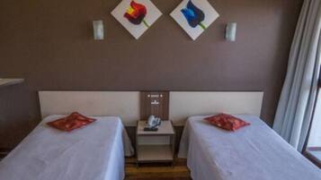 Habitación de hotel con dos camas, una mesita de noche y un teléfono instalado en la pared.