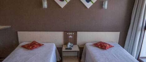 Een hotelkamer met twee bedden, een nachtkastje en een telefoon aan de muur.