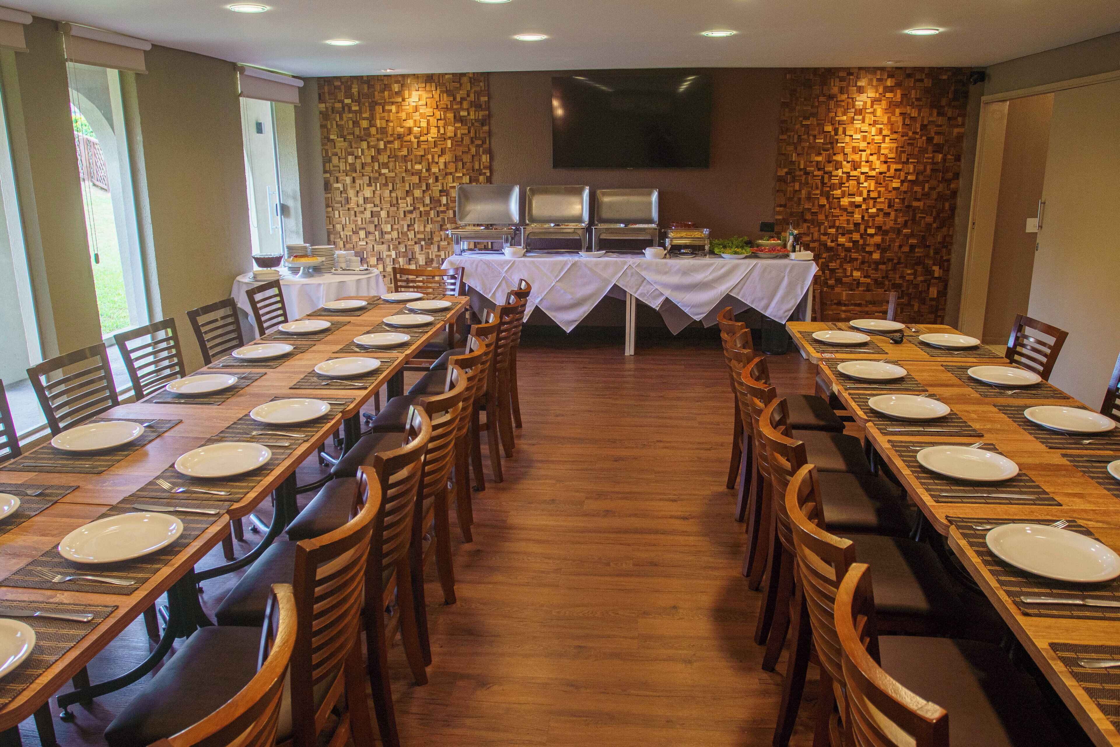 A large dining area with multiple tables set for meals, a buffet station, and a flat-screen TV mounted on the wall.