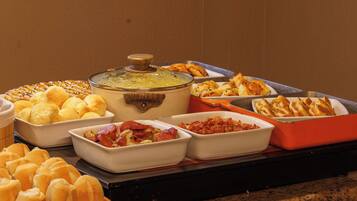 A buffet with various food items including bread, pastries, and a pot of soup.