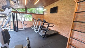A gym with treadmills, weight machines, and a brick wall. - SJ Jaguariaíva - San Juan Jaguariaíva (Jaguariaíva)