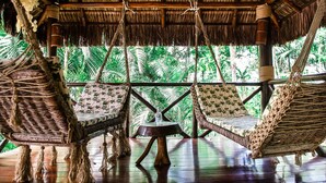 Una habitación con techo de paja, muebles de mimbre y vistas a un verdor exuberante.