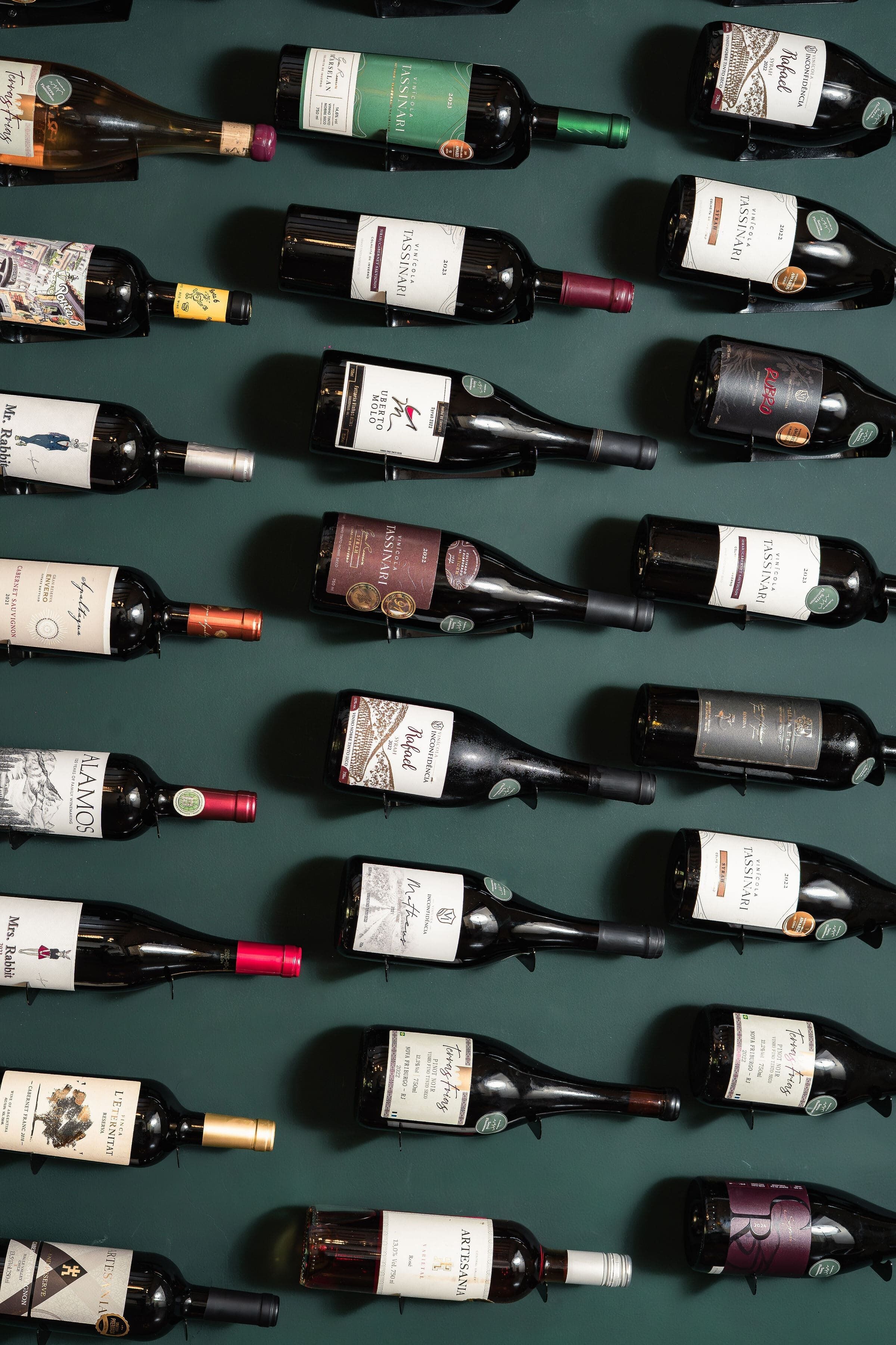 A collection of wine bottles arranged on a green surface.