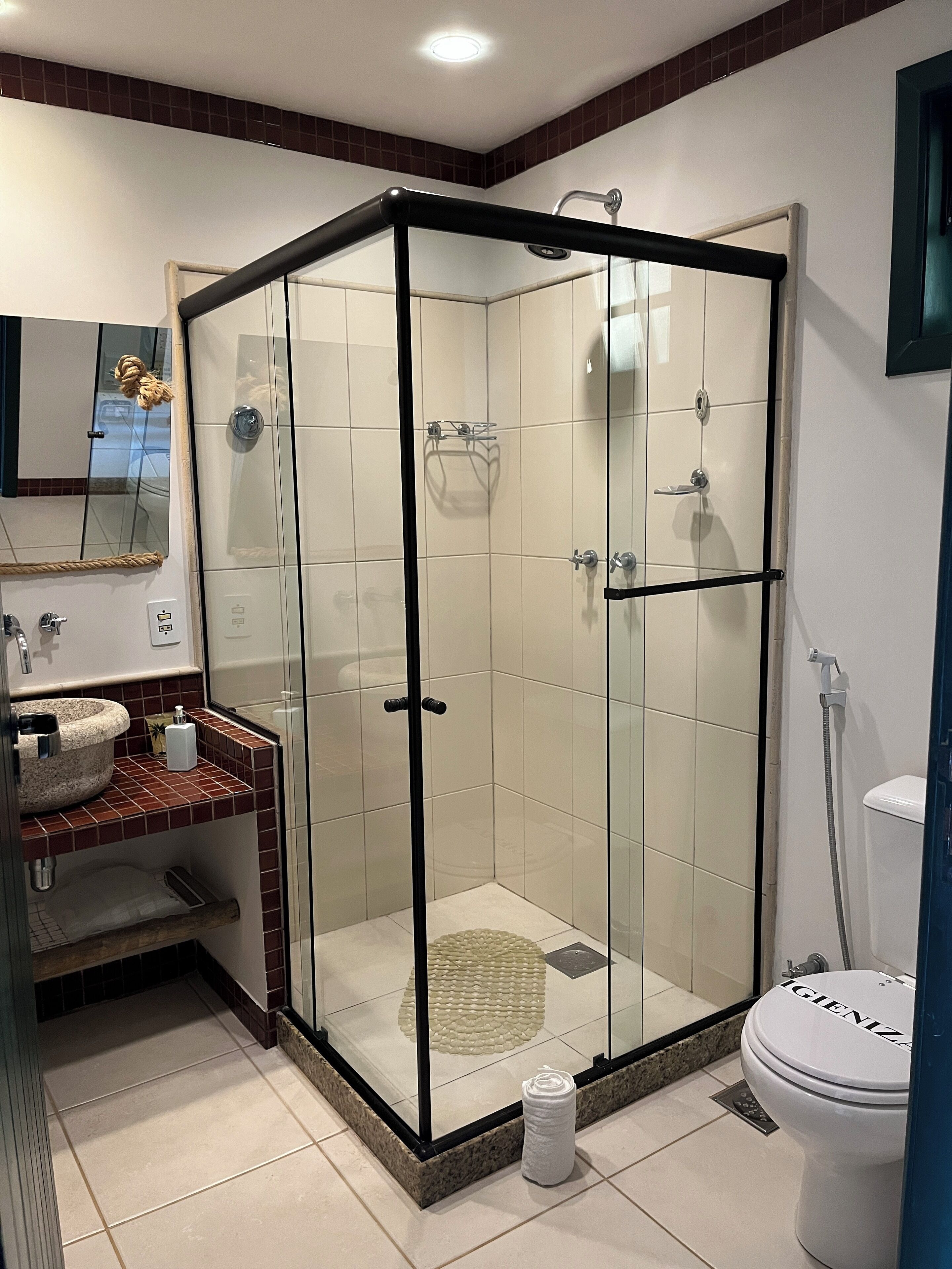 A modern bathroom with a glass-enclosed shower, a sink with a marble basin, and a toilet.