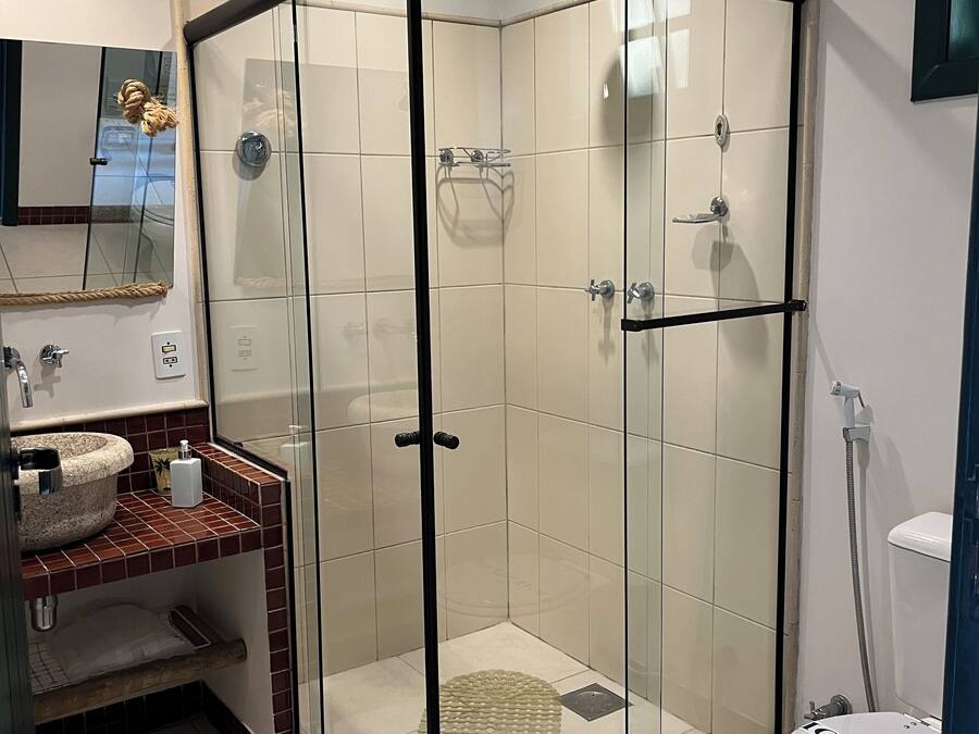 Une salle de bain moderne avec une douche à parois de verre, un lavabo avec un receveur en marbre et des toilettes.