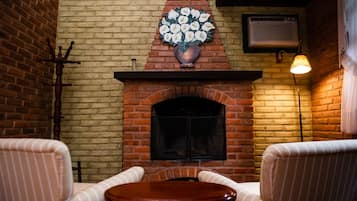 A cozy room with a brick fireplace, striped chairs, and a table.