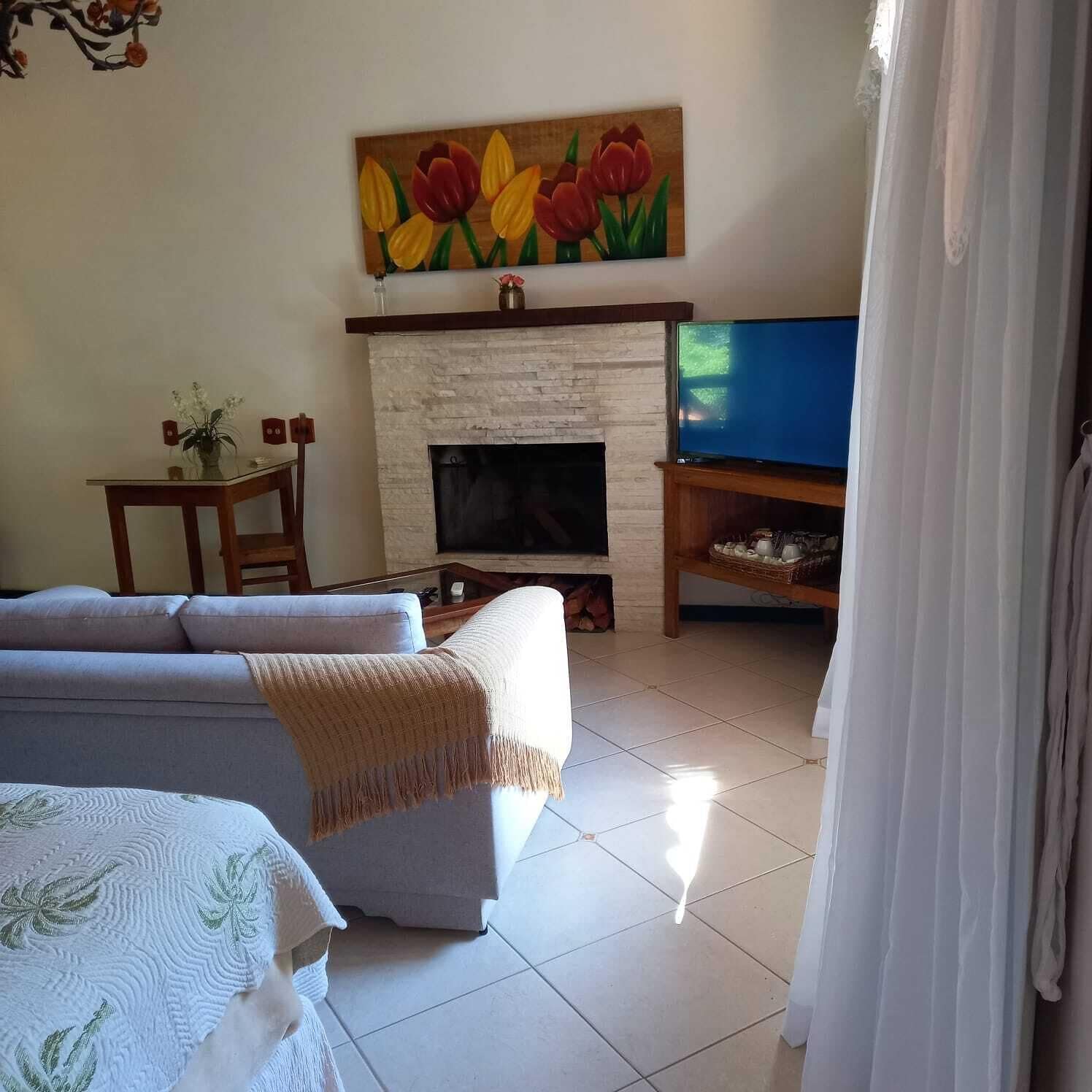 A living room with a fireplace, a television, and a painting of tulips on the wall.