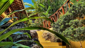 A staircase with a wooden railing leading up to a building, surrounded by lush greenery and tropical plants. - Charme Pousada Boutique & Spa (Cairu)