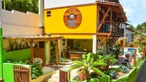 Un edificio de dos pisos con fachada amarilla y terraza de madera.