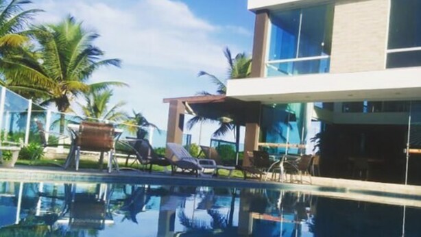 Ett modernt hotell med en pool med kristallklart vatten, solstolar och palmer.