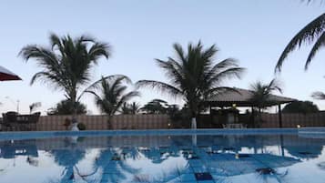 Una piscina al aire libre, sombrillas, sillones reclinables de piscina