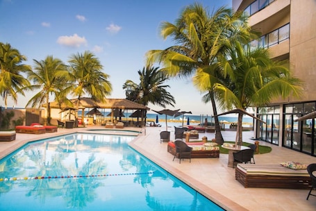 Una piscina al aire libre, sombrillas, sillones reclinables de piscina