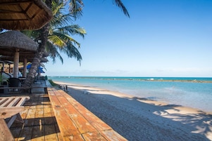 Na praia, areia branca, espreguiçadeiras, guarda-sóis