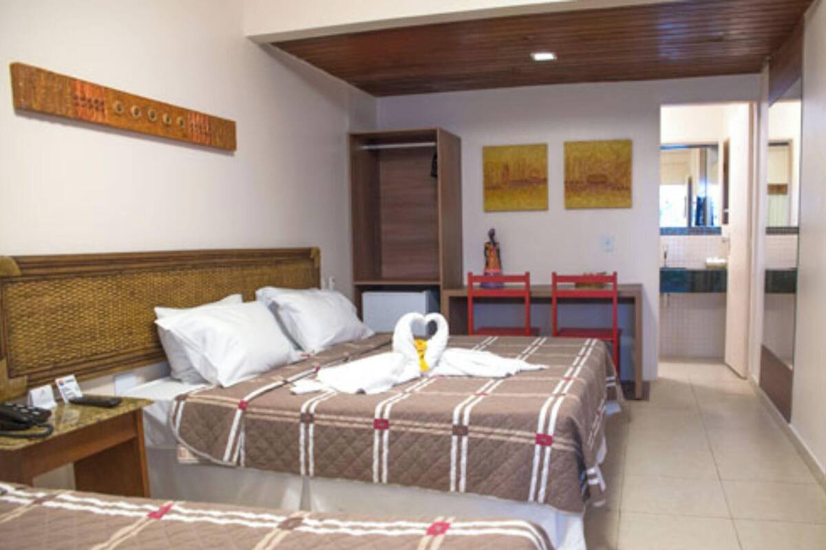 Habitación de hotel con dos camas, cabecero de madera, escritorio y televisor.
