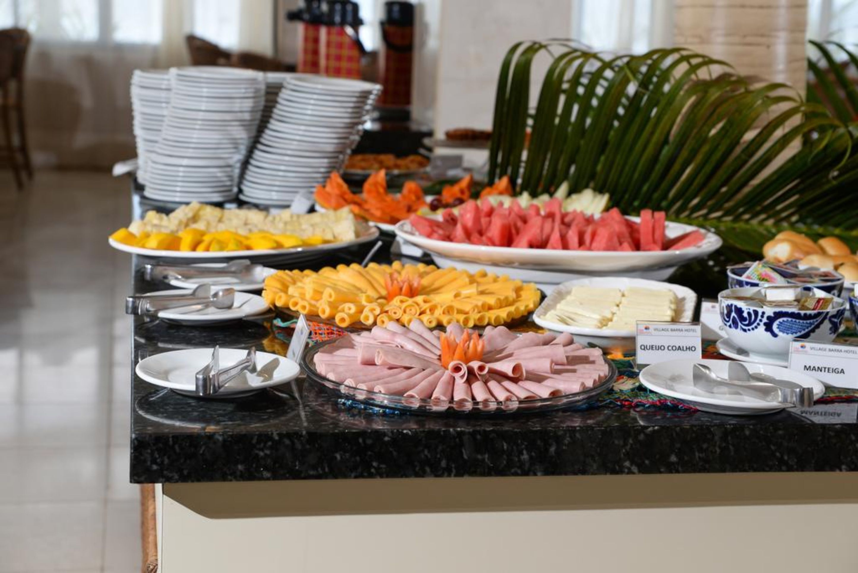 A buffet with various food items including cheese, ham, and fruits.