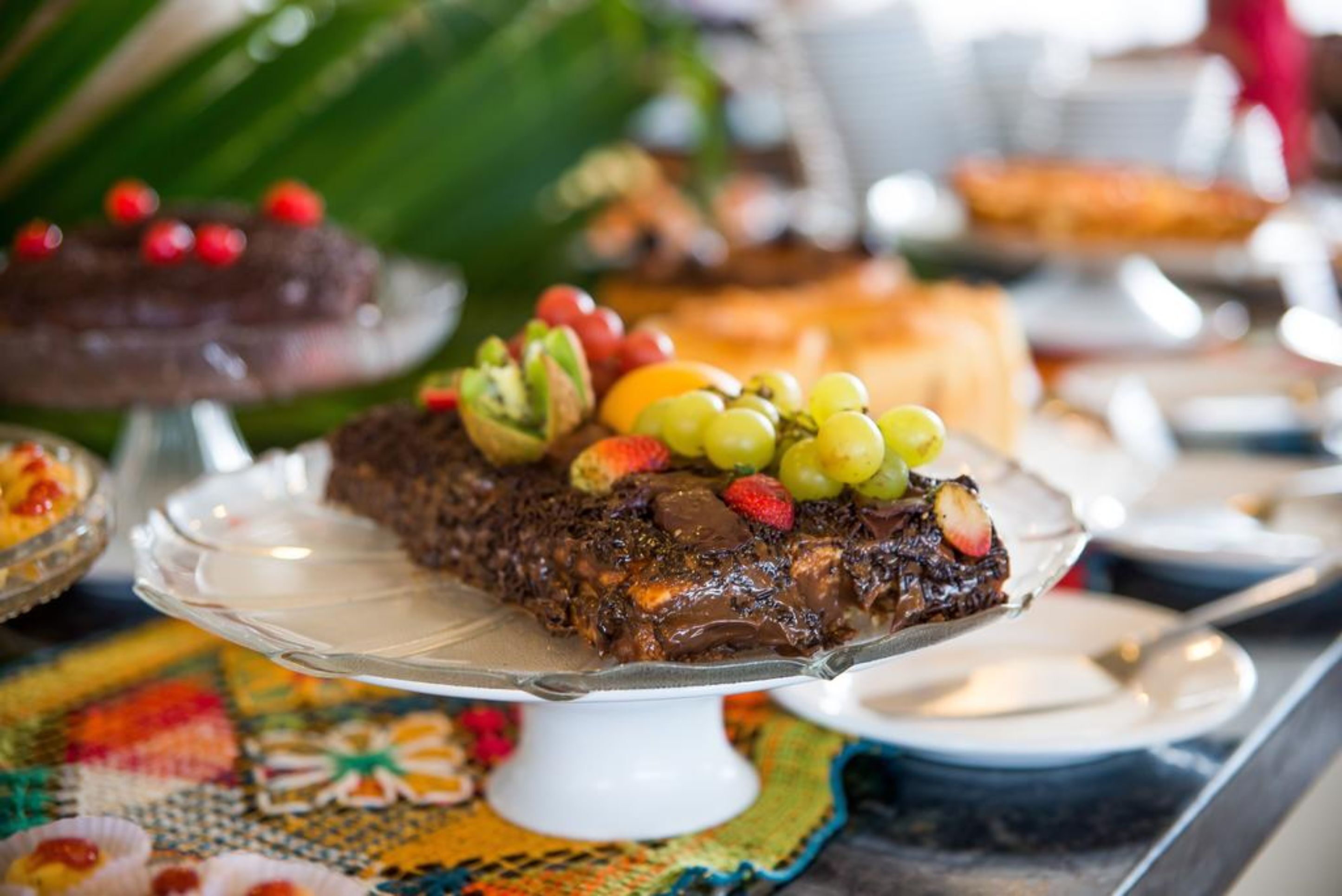 A dessert platter with chocolate cake and fruit on a white stand.