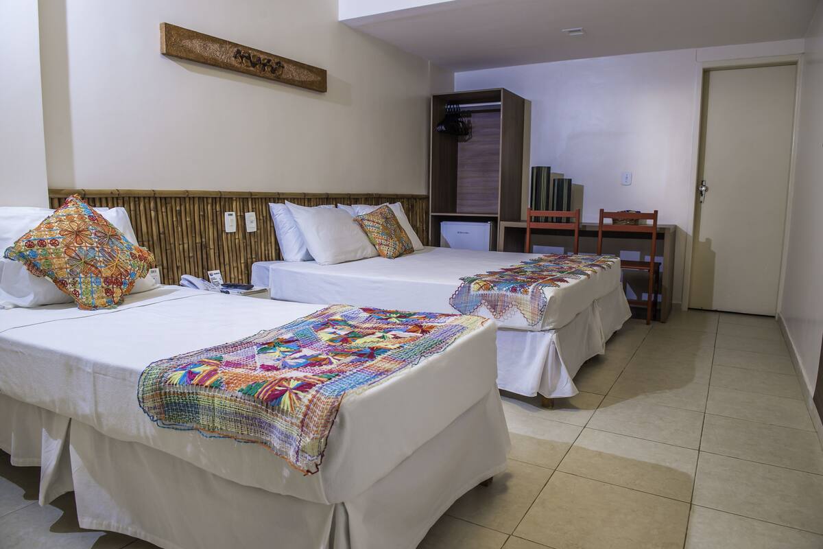 Habitación de hotel con dos camas, un escritorio y un armario.