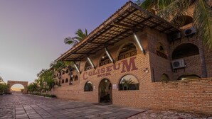 Un edificio de ladrillo con ventanas arqueadas y un letrero que dice 'Coliseum Hotel'.