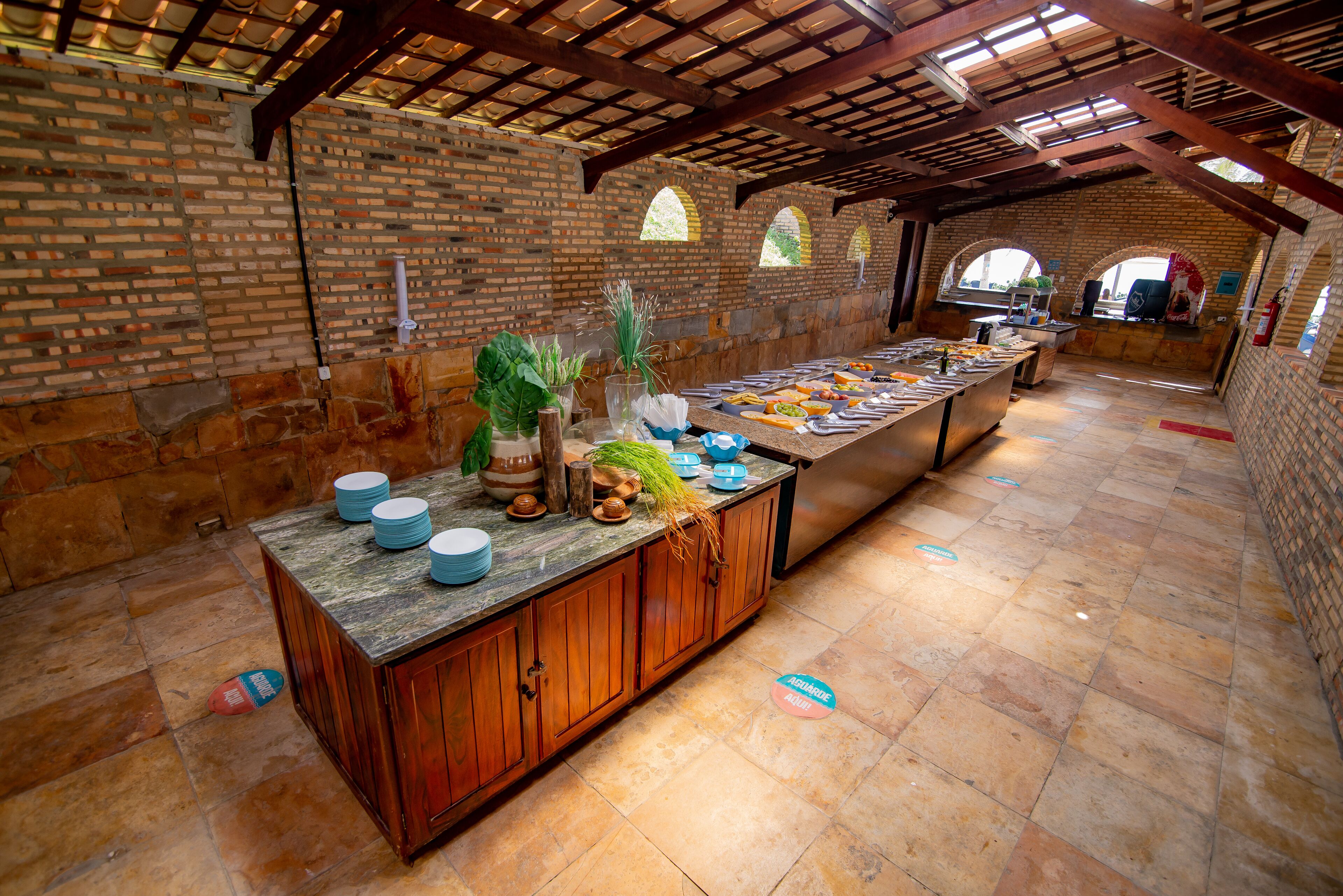 A long buffet table with various dishes, a brick wall, wooden cabinets, and arched windows.