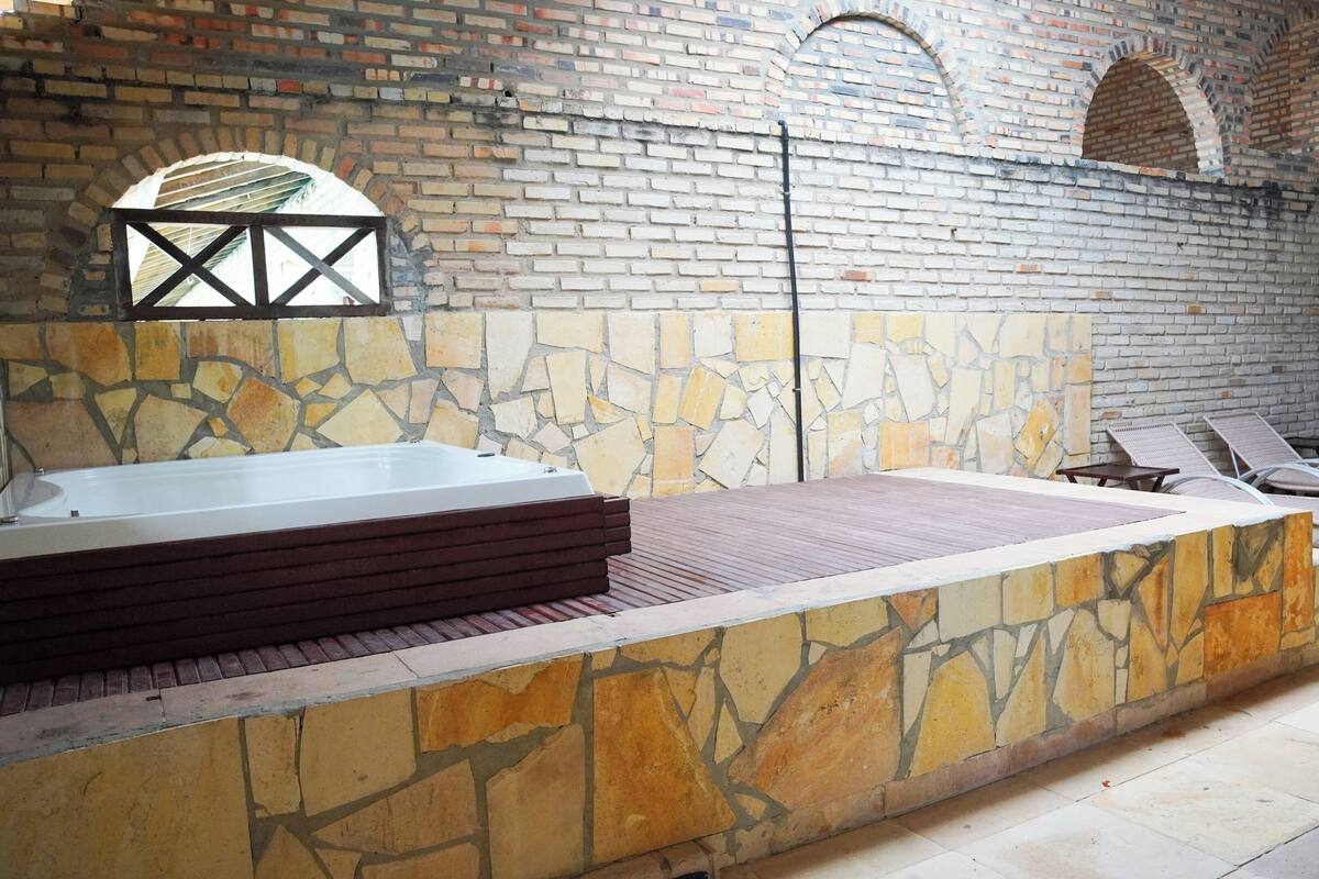 A spa area with a stone wall, a hot tub, and lounge chairs.