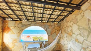 A stone-walled room with a view of the beach, a hammock, and a table with chairs. - Hotel Parque das Fontes All Inclusive (Beberibe)