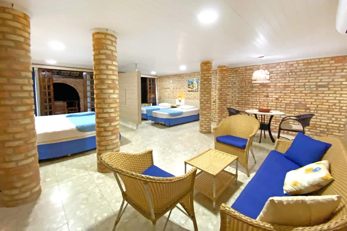 A hotel room with a brick wall, a fireplace, a sofa set, and a small dining table.