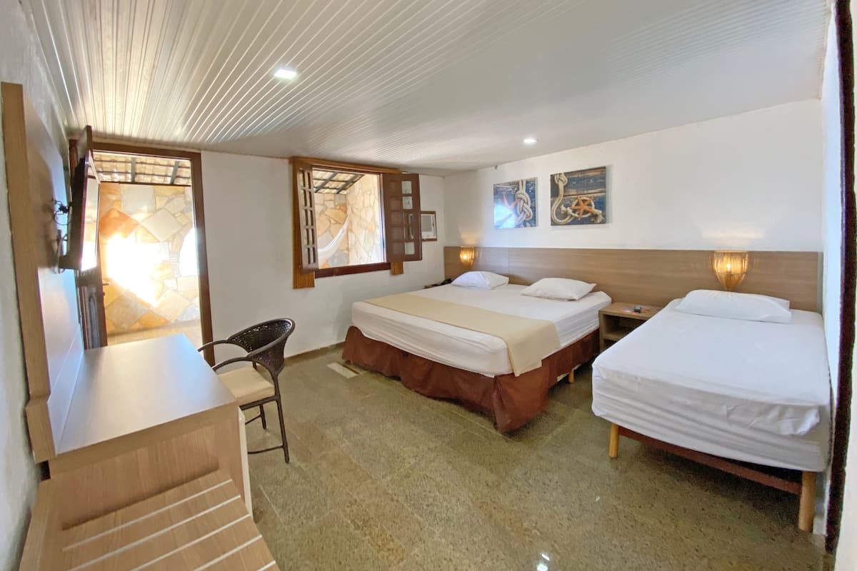 A hotel room with two beds, a desk, a chair, and a large window.