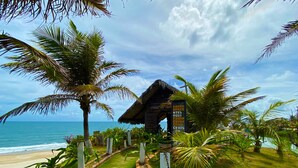 A tropical resort with a thatched-roof hut, palm trees, and a pathway leading to the beach. - Hotel Parque das Fontes All Inclusive (Beberibe)