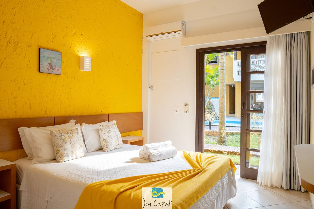 A hotel room with a bed, a nightstand, a wall-mounted light, and a door leading to an outdoor area.
