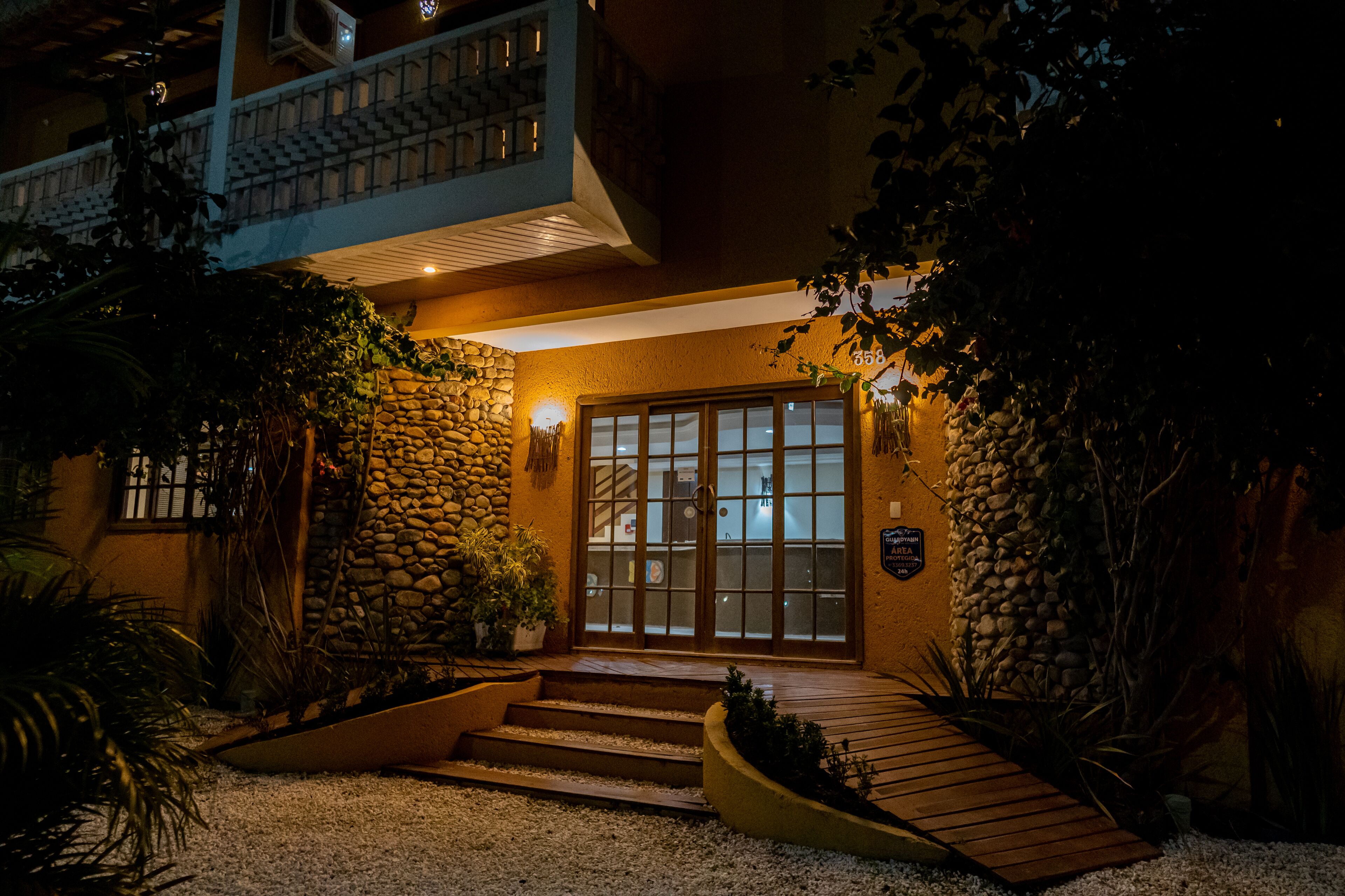 Entrada de hotel com fachada de pedra, degraus de madeira e portão.