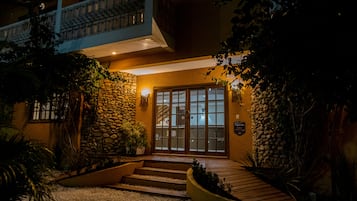 Entrada de hotel com fachada de pedra, degraus de madeira e portão.