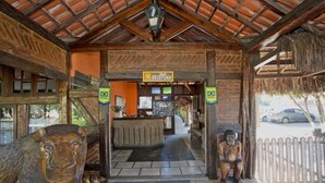 A reception area with a sign reading "RECEPCAO" and a Brazilian flag. There are wooden sculptures on either side of the entrance. - Quari Quara BY MN Hotéis (Rio das Ostras)