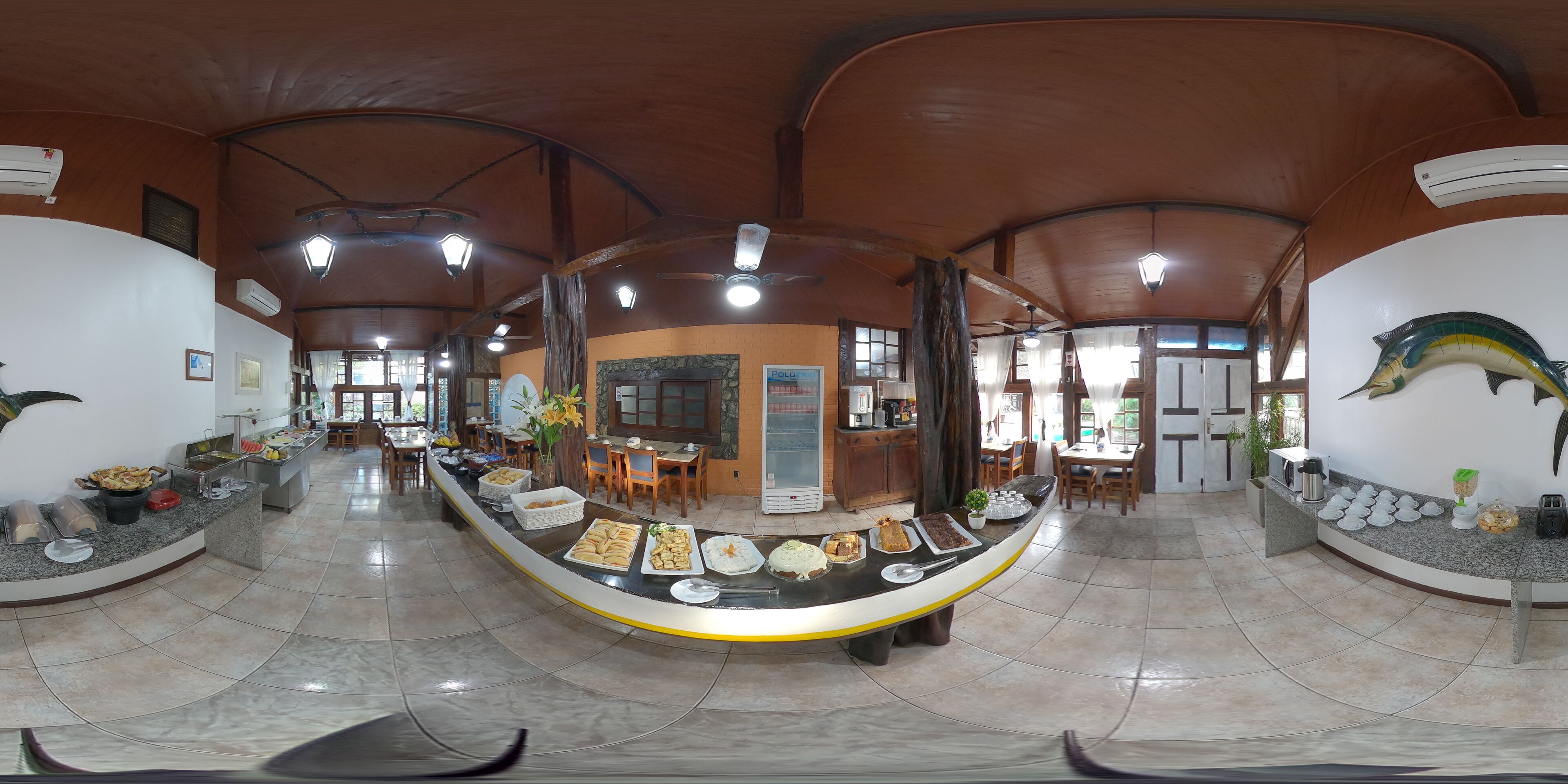 A spacious, well-lit dining area with a curved counter displaying various food items and a central seating area with tables and chairs.