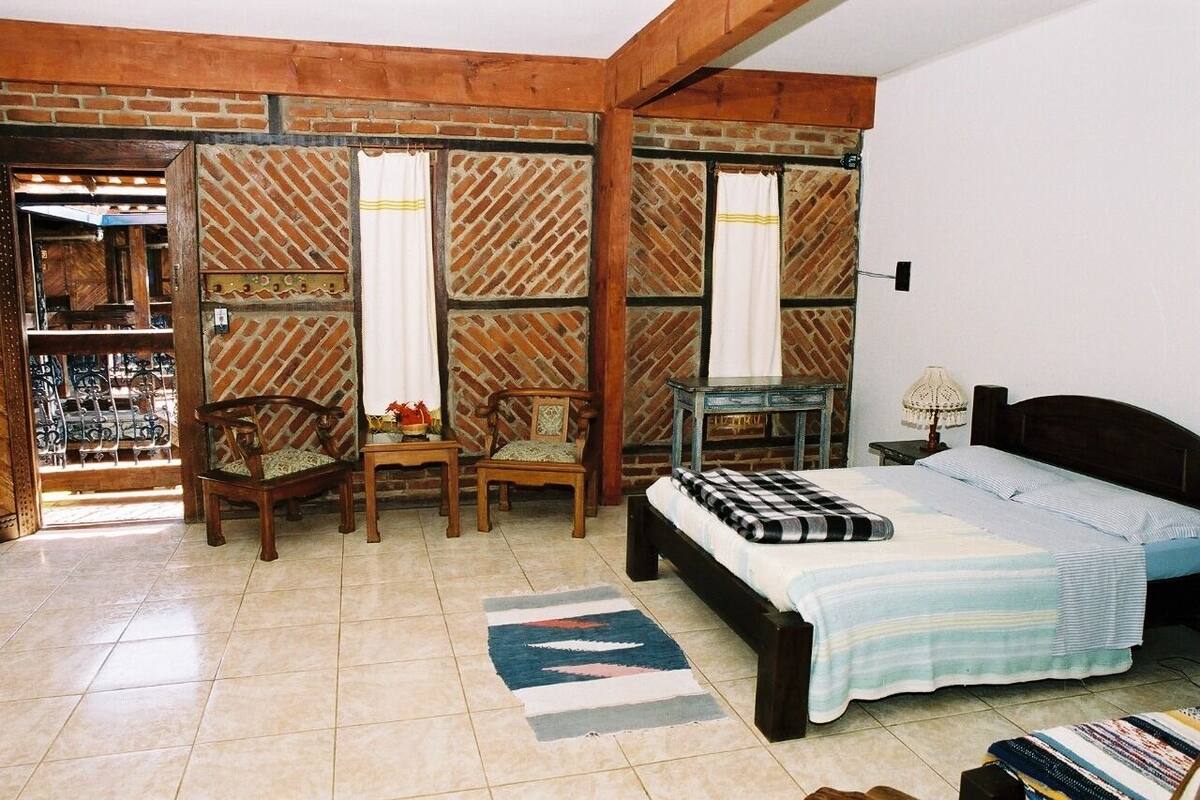 A bedroom with a bed, two chairs, a small table, and a nightstand.