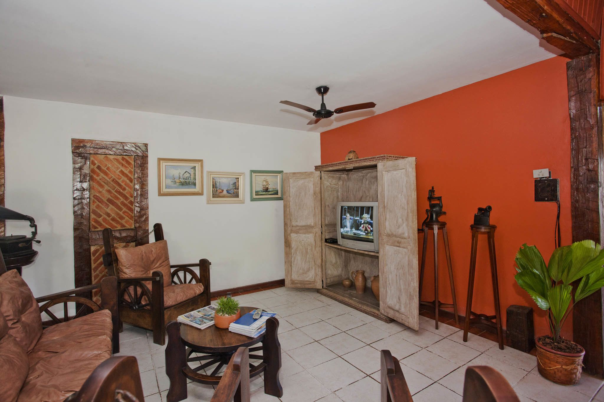 A living room with a television, wooden furniture, and a ceiling fan.