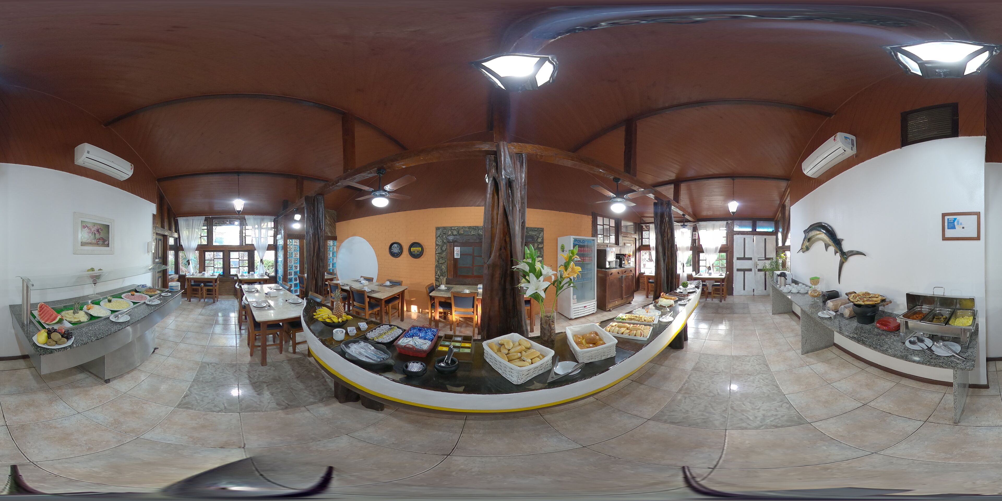A spacious dining area with a curved buffet table, ceiling fans, and natural light from windows.