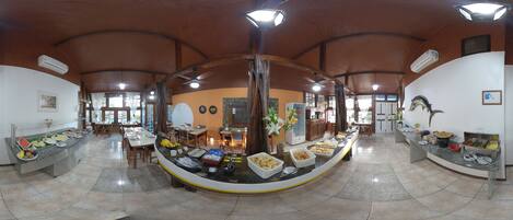 A spacious dining area with a curved buffet table, ceiling fans, and natural light from windows.