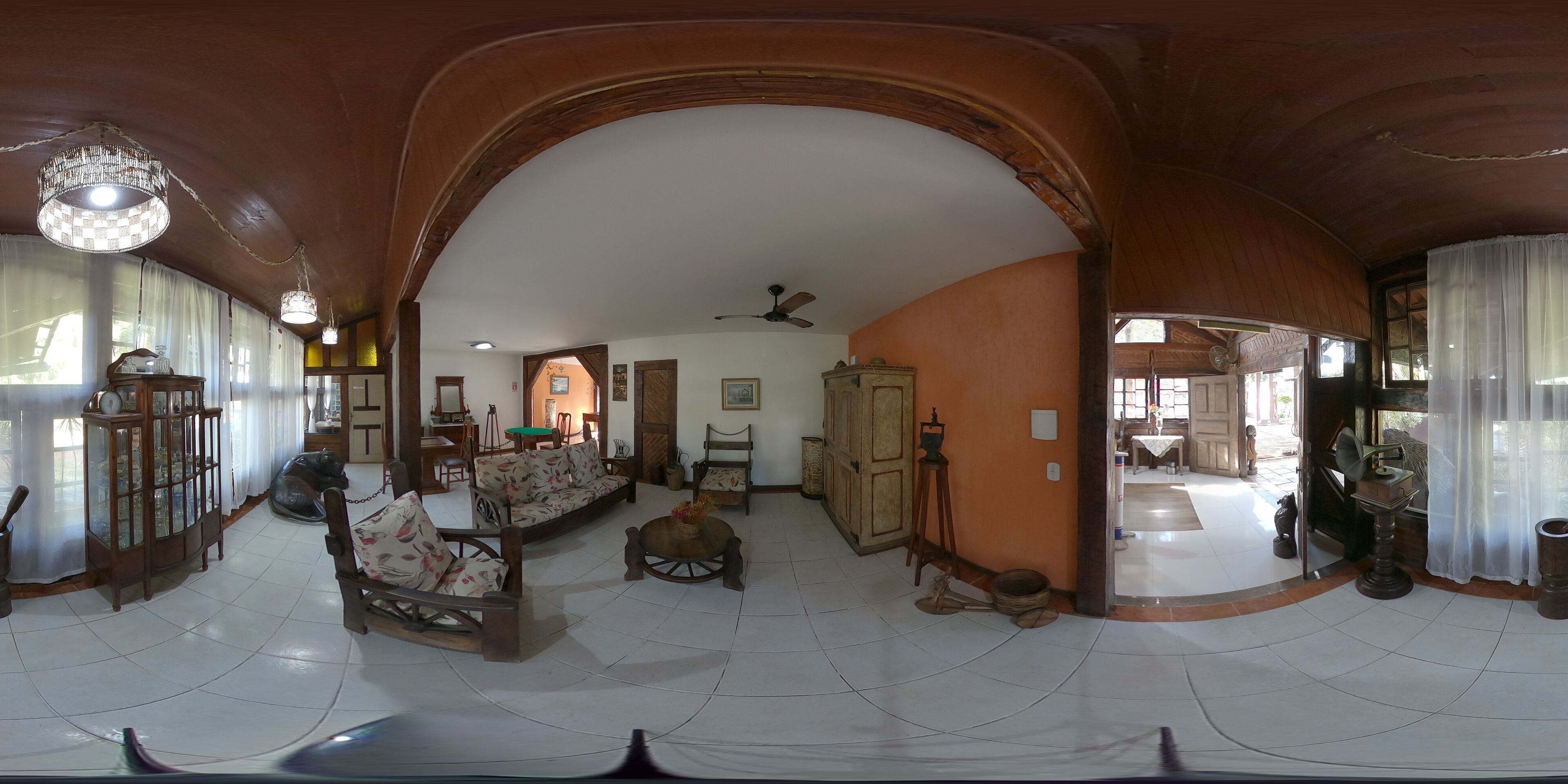 A spacious living room with a high ceiling, wooden furniture, and a large arched doorway.