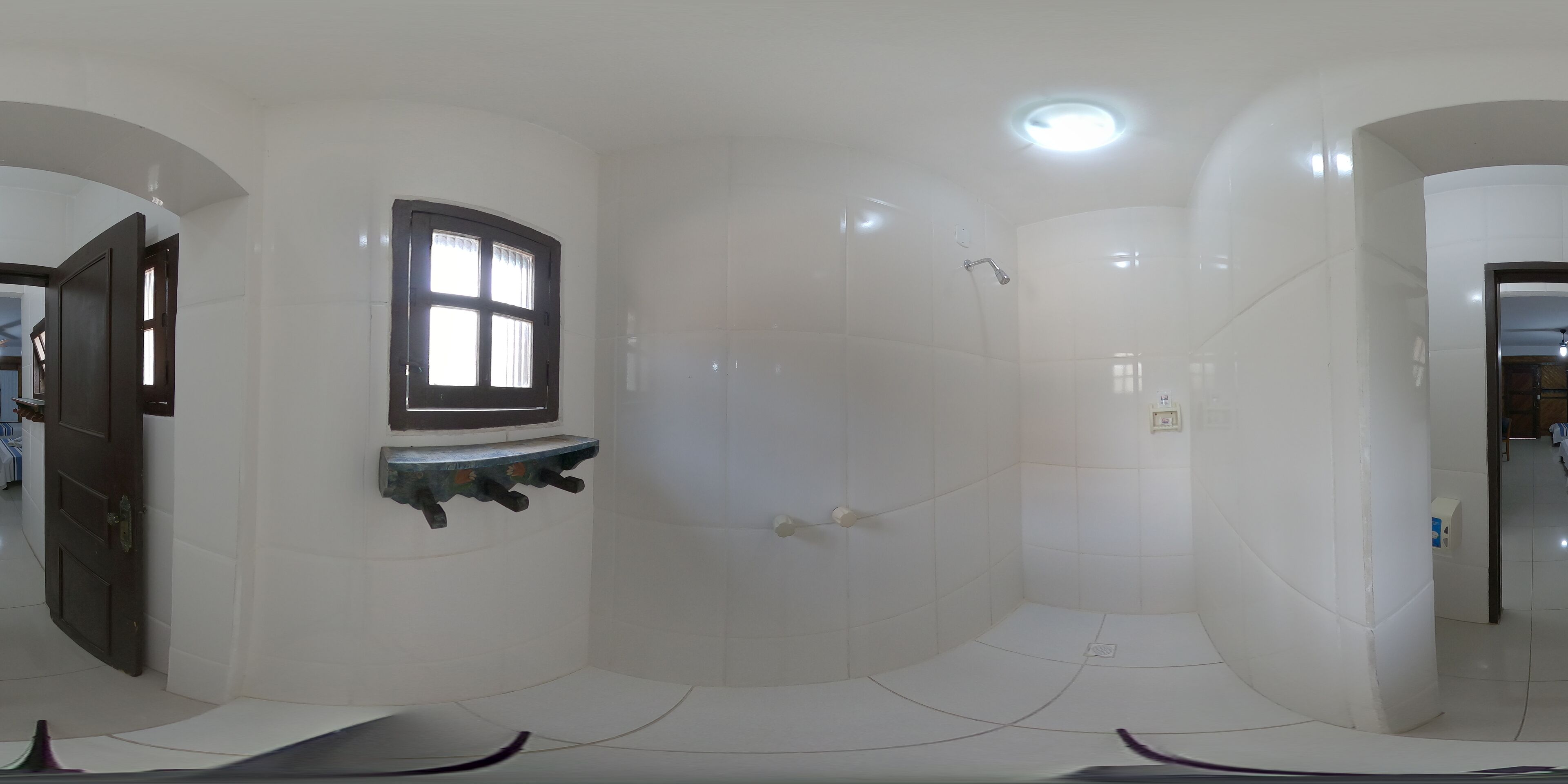 Un baño moderno con baldosas blancas, una ventana y zona de ducha.