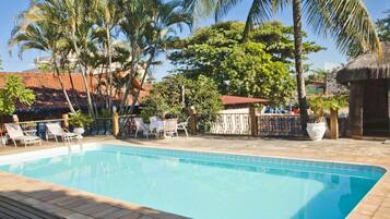 Relax by the serene pool surrounded by lush greenery and palm trees.