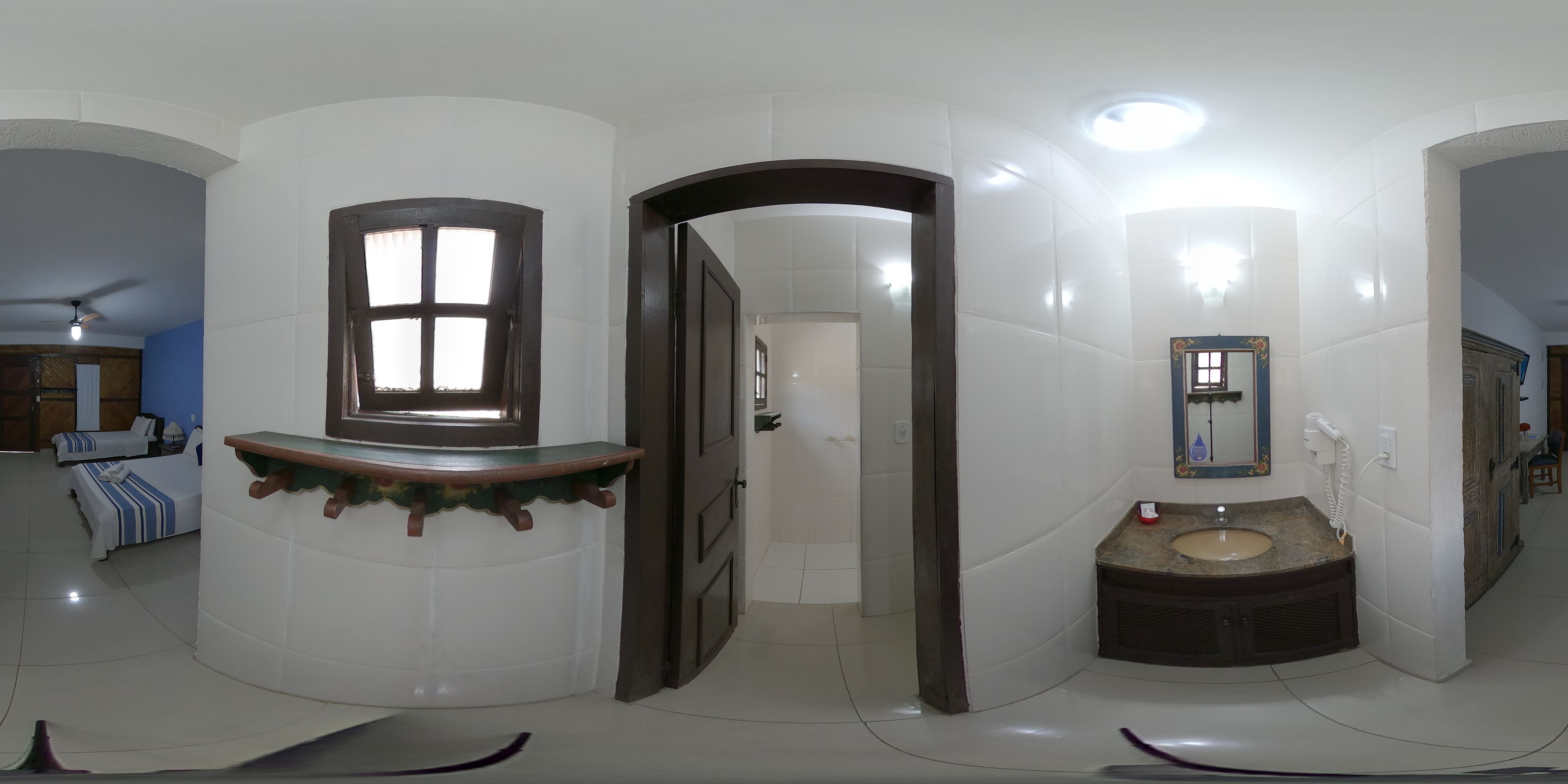 Une salle de bain d’hôtel avec un lavabo, un miroir et une porte donnant sur une autre pièce.