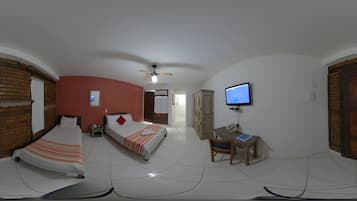 Una habitación con dos camas, un escritorio, un televisor y un ventilador de techo.