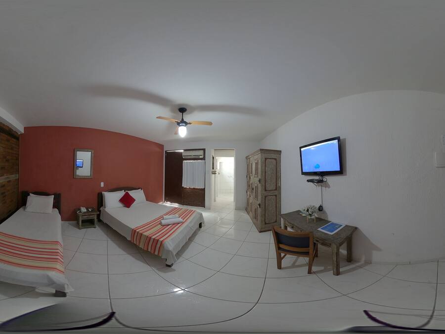 Una habitación con dos camas, un escritorio, un televisor y un ventilador de techo.