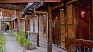 A corridor with brick walls, wooden doors, and metal railings. - Quari Quara BY MN Hotéis (Rio das Ostras)